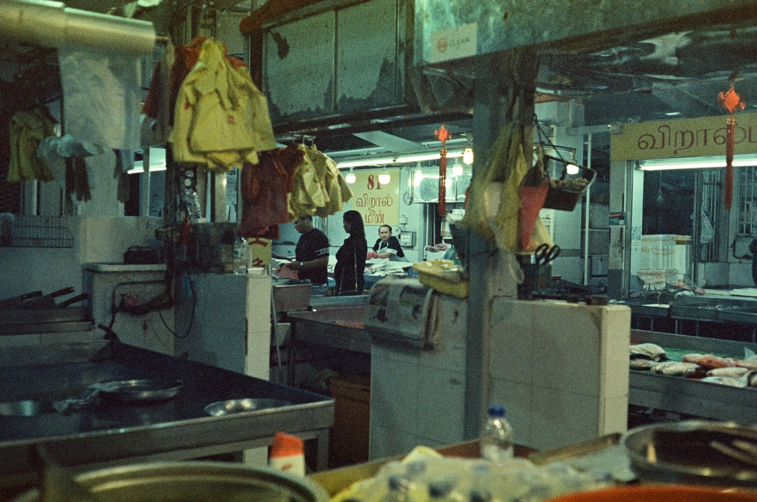 MISO 400 film capturing a low-light market scene with hanging items and people working in dim lighting.