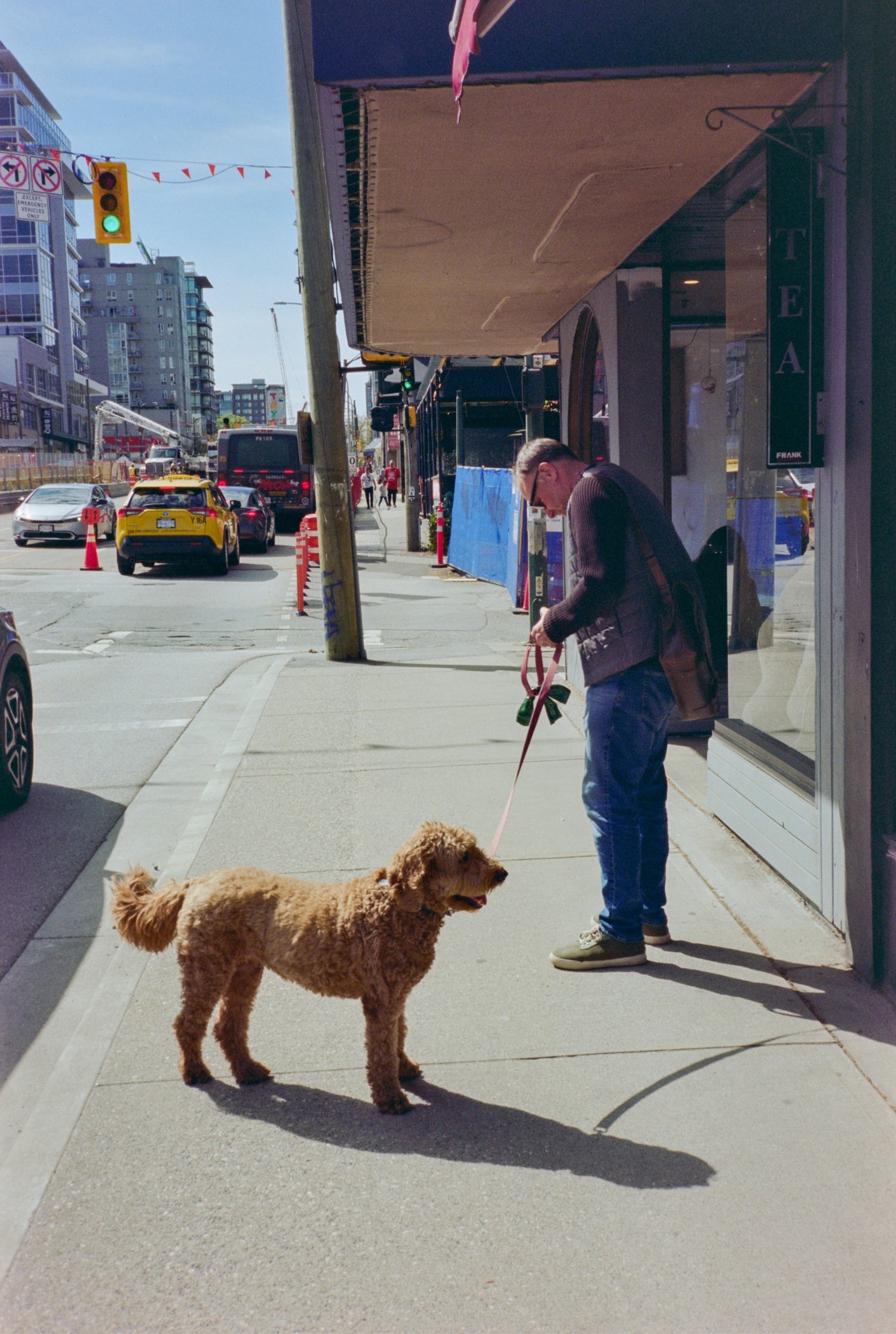 Man walking dog on a busy street shot on MISO 200 film with medium grain