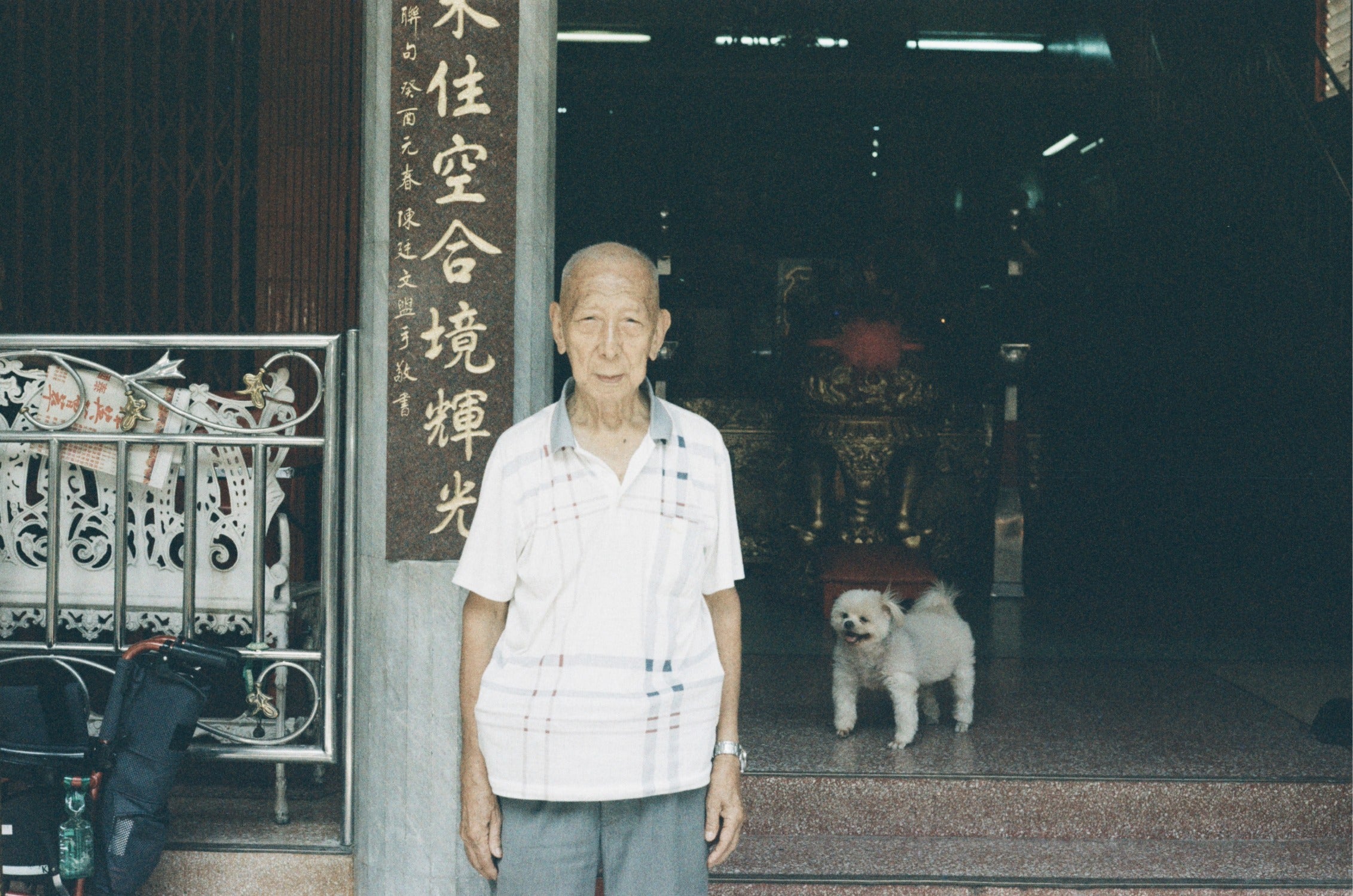 URBAN 400 high grain film photo of an old man and his dog outside a building in Bangkok.