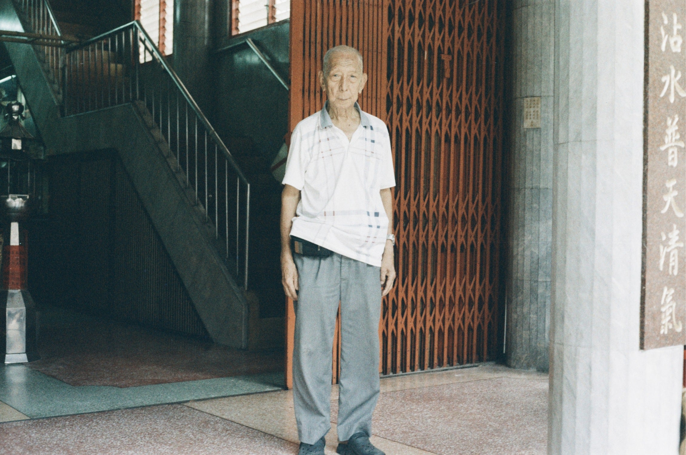 URBAN 400 film capturing an old man standing in front of a gate with high grain texture.